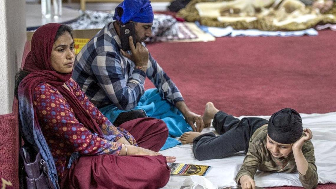 Inside the Gurdwara Sahib Sikh temple, Diljit Singh, 7, eats french fries as his mother, Ramandeep Kaur, left, and father, Baltwant Singh, 49, center, rest after evacuating from Yuba City the night before on Monday, Feb.13, 2017, in West Sacramento, Calif.