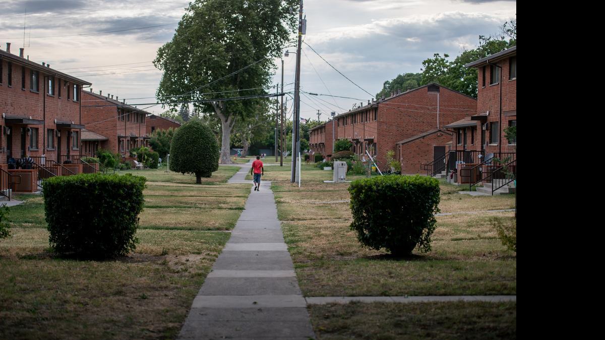 
A man walks at the Alder Grove housing project, where some residents have mixed feelings about a mixed-use neighborhood plan for the site.
