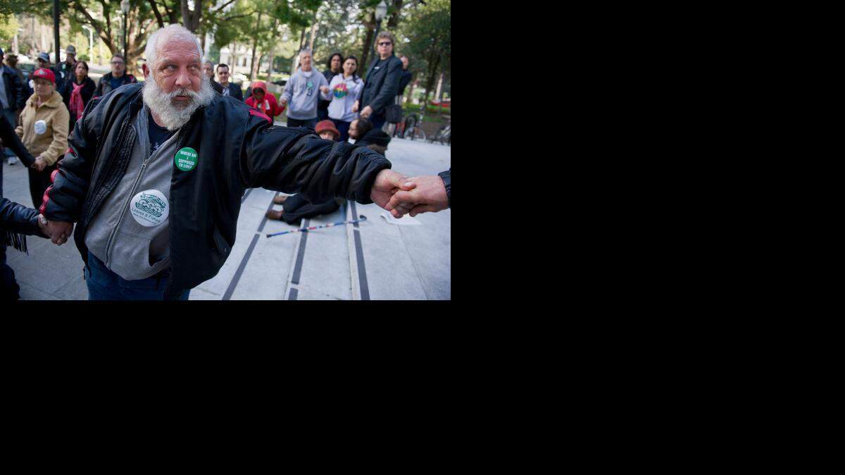
Thomas Martin, who is homeless, holds hands in solidarity during a gathering to protest a city ordinance that prohibits camping on public and private property in January. In arguments before the 3rd District Court of Appeal, Sacramento argued that it protects private property owner’s rights against trespassers.
