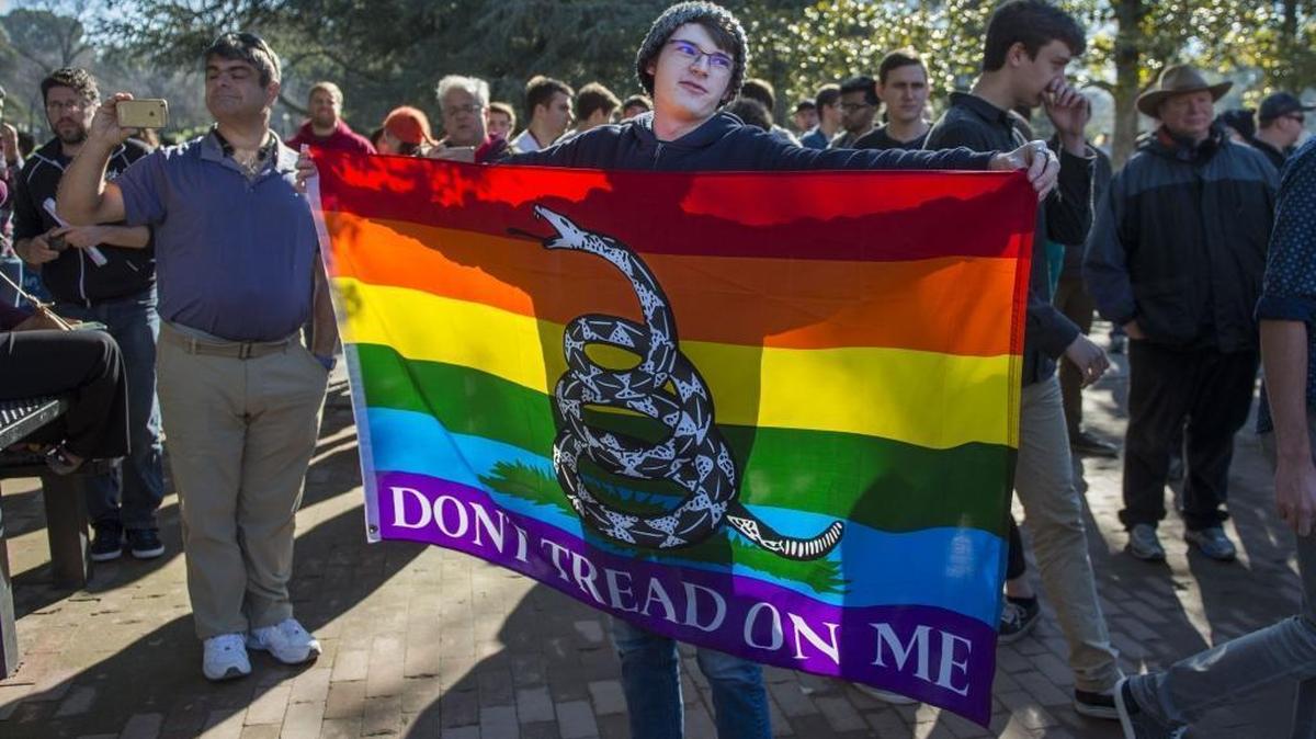 Nicholas Francois, a Log Cabin Republican and UC Davis student, holds a Gadsden flag combined with the gay pride flag before the march on the UC Davis campus Saturday with controversial speaker Milo Yiannopoulos.