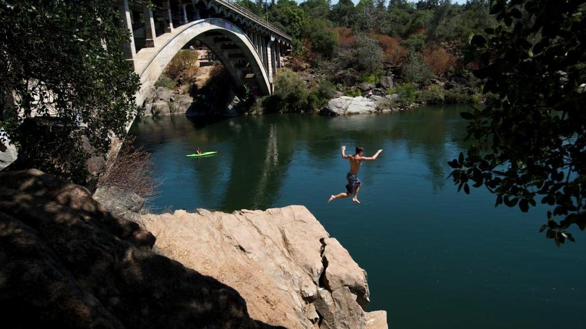 An adventure-seeker jumps off the rocks into the water below the Rainbow Bridge in 2015.