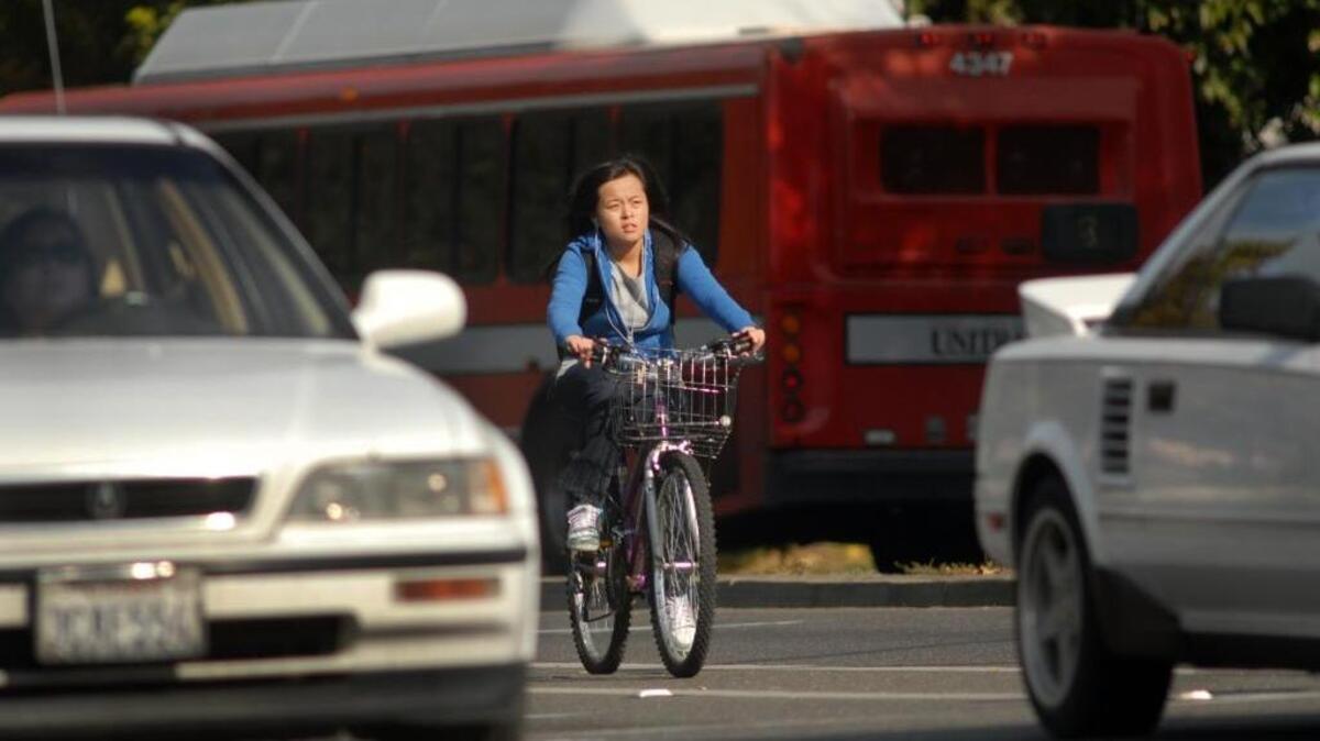 A bicyclist rides alongside cars, trucks and buses at the corner of La Rue Road and Russell Blvd in Davis, Wednesday, November 12, 2008.