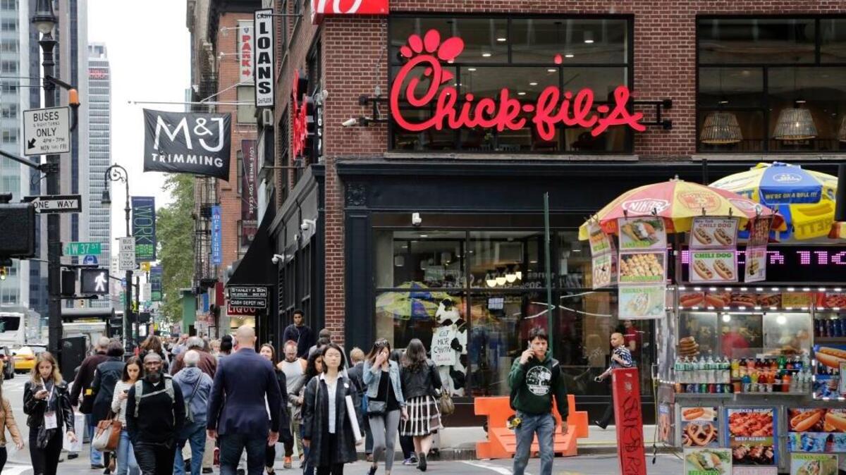 People walk past a new Chick-fil-A restaurant, Thursday, Oct. 1, 2015 in New York. The fast food chain is offering a free entree for anyone who dresses up in a cow costume or wears a cow-spotted accessory.