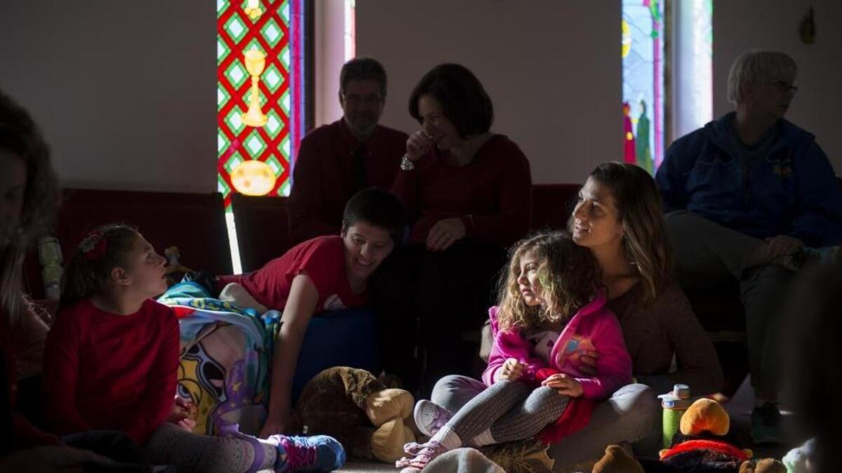 Kadie DeMar, right, holds her daughter Cameron DeMar, 4, while encouraging her daughter Brooke, at left, who has cerebral palsy, during a special Christmas church service for kids on the autism spectrum and other special needs Saturday at St. James Episcopal Church in Lincoln.