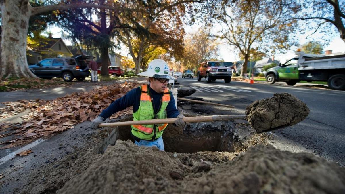 A worker with Teichert Construction digs a hole on Land Park Drive south of Second Avenue as part of a water infrastructure project by the city of Sacramento on Monday, Nov. 24, 2014.