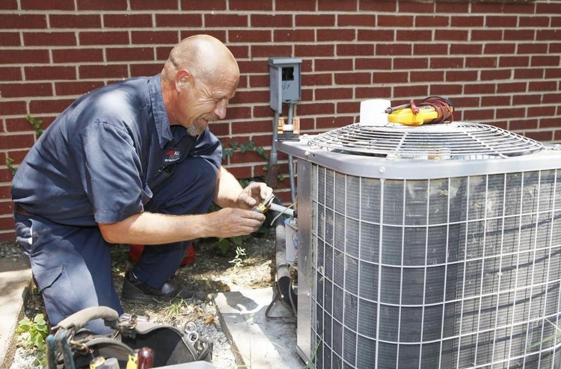 Russ Schuh, with Doo All Services, replaces a capacitor in an air-conditioning unit at a home in Benjamin Hills, Kan., on June 28, 2012.
