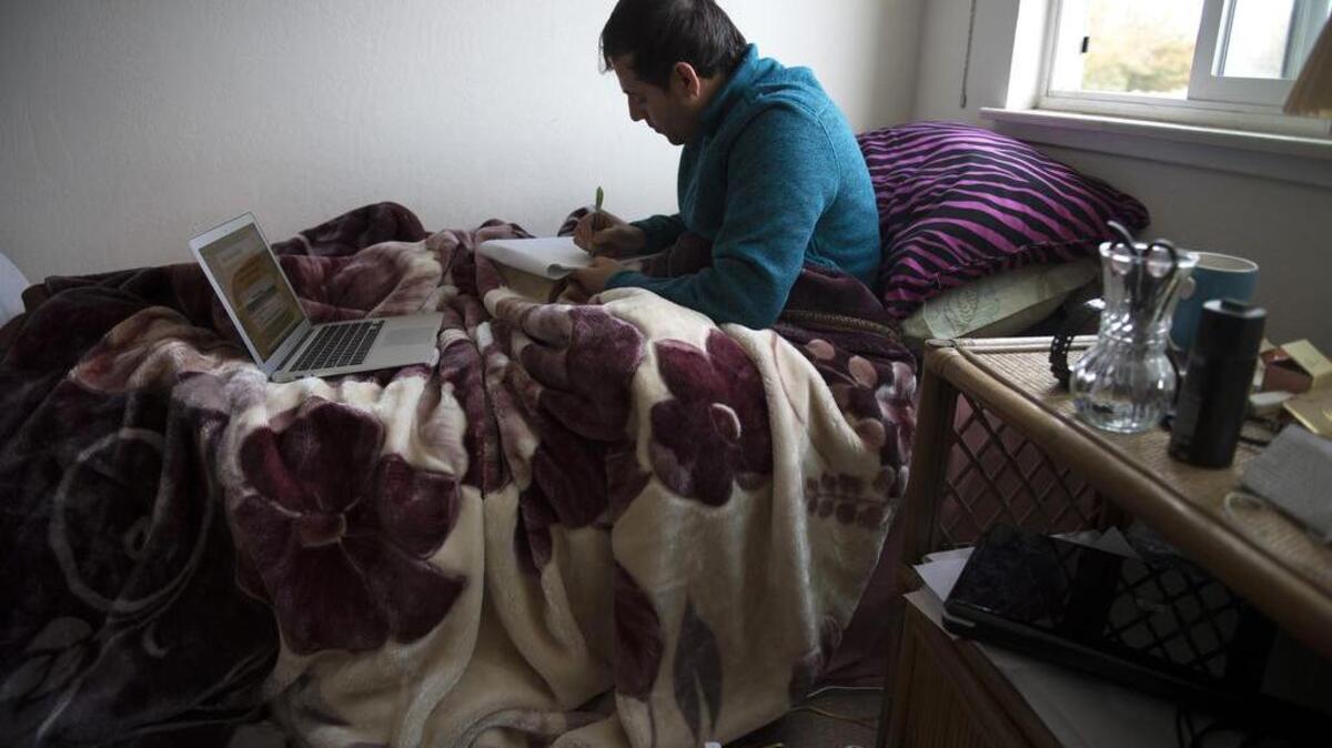 Afghan Special Immigrant Visa holder Naimatullah Sultani, 27, a workforce development specialist with Lao Family Community Development Inc. and a social science and business administration student at American River College, studies in the bedroom he shares with another visa holder on Oct. 30 in Sacramento. Sultani worries about keeping up his 4.0 grade-point average and juggling his job helping other Afghan refugees get jobs. He says he studies in the bedroom to give his roommate Ajmal Shahab, 26, privacy to study in the living room and kitchen area of the two-room apartment.