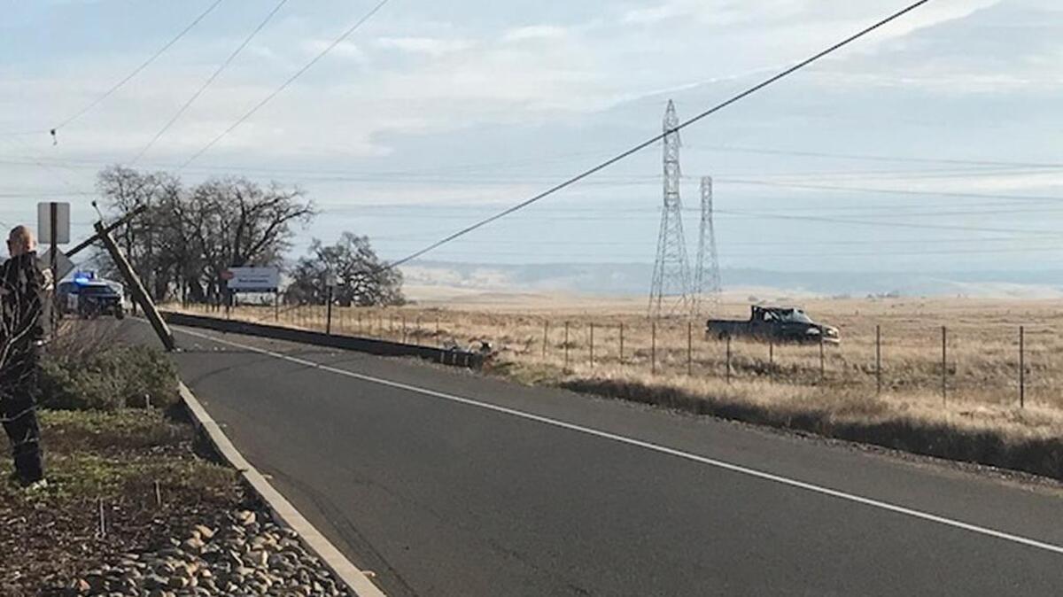 A dark-colored truck sits in a field after crashing into a power pole Friday along White Rock Road.