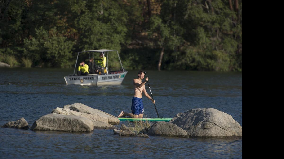 
Michael Szeman, 24, paddles to shore as a State Parks patrol boat searches the area at Rock Beach at Negro Bar for a 23-year-old man drowned just before 4 p.m. as he swam with three others on Thursday, July 16, 2015, in Folsom. The victim was found Tuesday morning and identified as Paul Liu of Sacramento.
