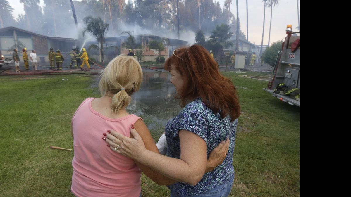 
As firefighters battle to save her mobile home, Kim Korth, right, co-owner of Korth's Pirate's Lair Marina, is comforted by her friend, Tracy Holcombe, Thursday, July 30, 2015, in Isleton,Calif. Fire crews from multiple agencies battled the fire that destroyed multiple homes and damaged several others.
