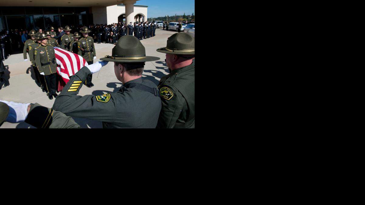 
Placer Sheriff's Deputy Jeff Davis salutes the casket of his comrade, Michael Davis Jr., whose casket is moved to a waiting hearse during a memorial service at Adventure Christian Church on Tuesday, Nov. 4, 2014, in Roseville, Calif. Saluting with left hand, Jeff Davis was shot during the shooting rampage and wears a sling on his right arm.

