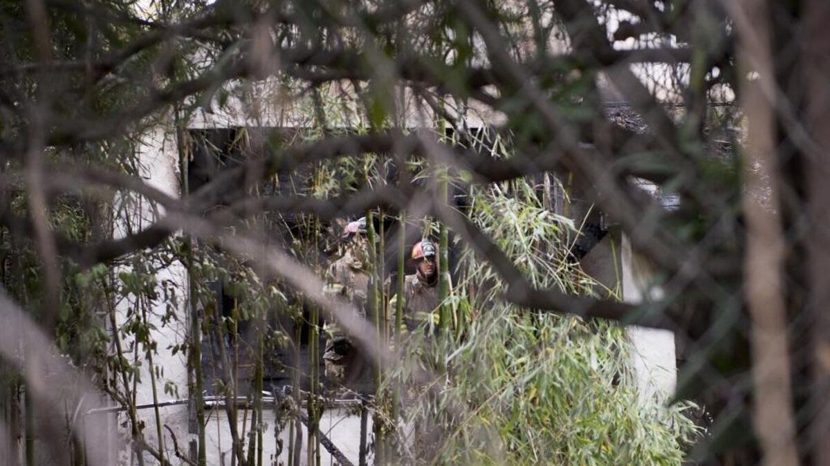 Sacramento Metro firefighters stand inside a fenced-in home surrounded by shrubbery where a fire broke out early Wednesday morning that claimed the life of an elderly Citrus Heights woman.