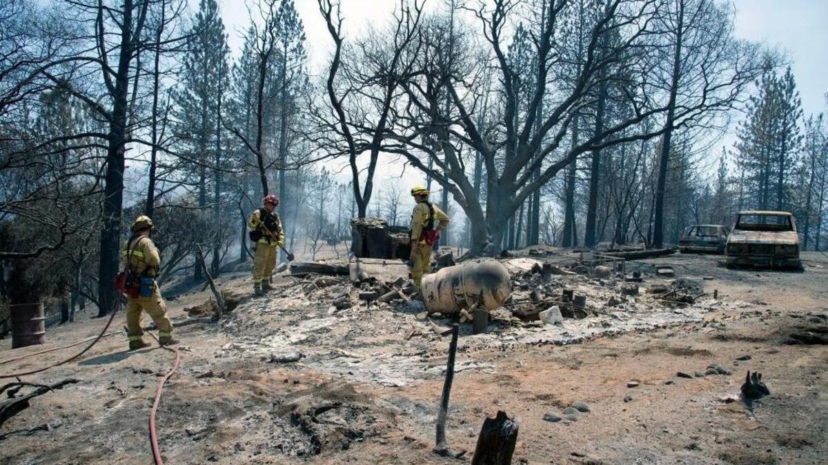 Firefighters from the Lathrop-Manteca Fire District mop up hot spots at a home that was destroyed along Lumpkin Road in Feather Falls.