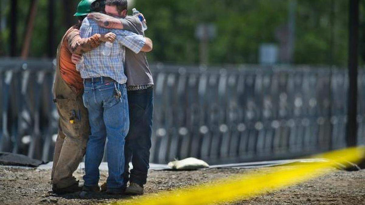 Three men hug near where the bodies of two workers were recovered after they died Friday morning when their crane-hoisted lift basket fell 80 feet at a bridge construction site on Putah Creek in Winters. The basket landed on timbers covering a 30-foot hole dug for footings for the new span. The 10-worker crew included the father of one of the men killed, said Richard Disney, president of Burlingame-based Disney Construction, which was building the bridge.