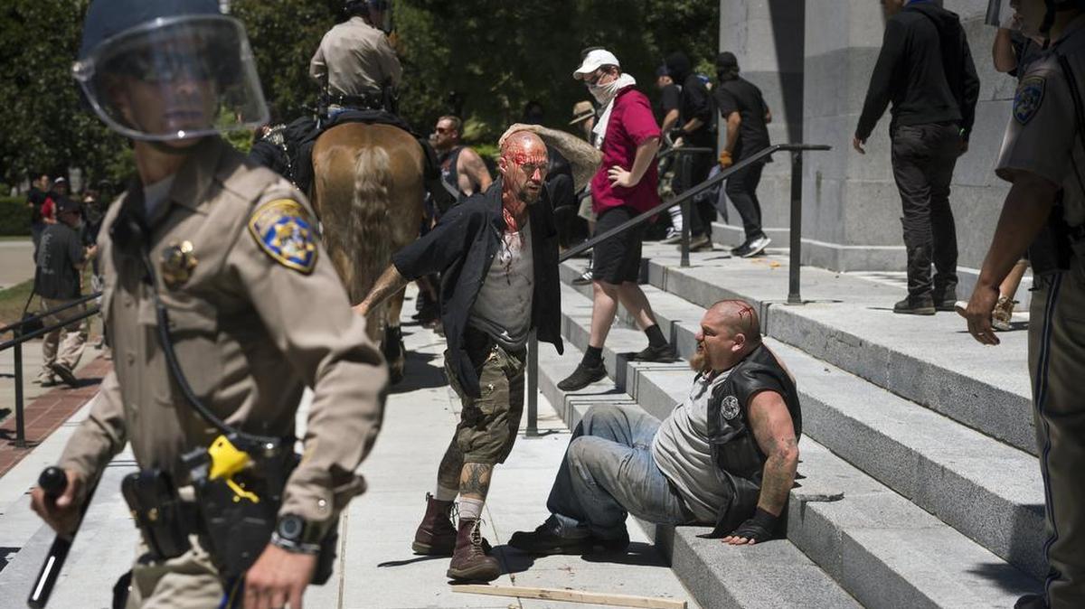 Two men are bloodied after a clash broke out between neo-Nazi anarchists and anti-fascist protesters at the State Capitol on Sunday, June 26, 2016 in Sacramento, Calif. Multiple people were stabbed as member of the group ANTIFA Sacramento (Anti-Fascism Action) counter-protested against the Traditionalist Worker's Party and the Golden State Skinheads.