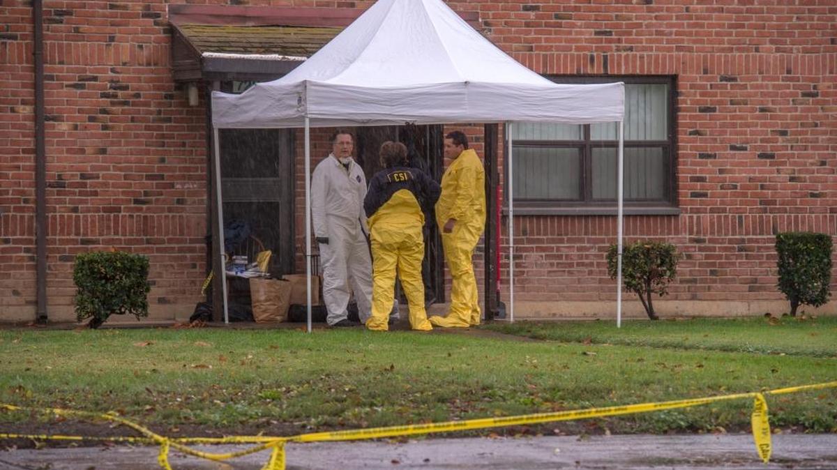 Crime-scene investigators shield themselves under a tarp Sunday, Oct. 16, 2016, at a home where two men and a woman were found dead the night before in the 700 block of Broadway in Sacramento.
