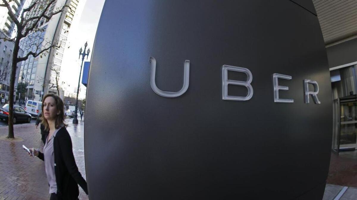 FILE - In this file photo taken Tuesday, Dec. 16, 2014, a woman walks past the company logo of the internet car service, Uber, in San Francisco.