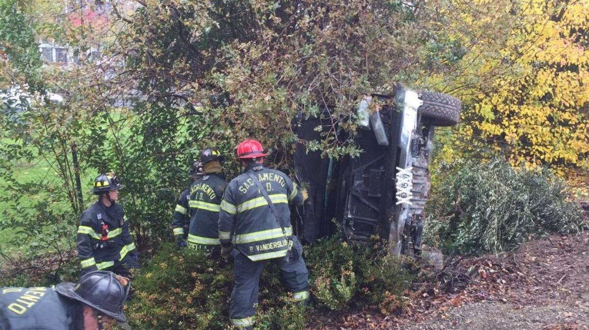 Sacramento Fire Department personnel tend to a vehicle that rolled over onto an embankment Friday morning off Interstate 5 at the Garden Highway.