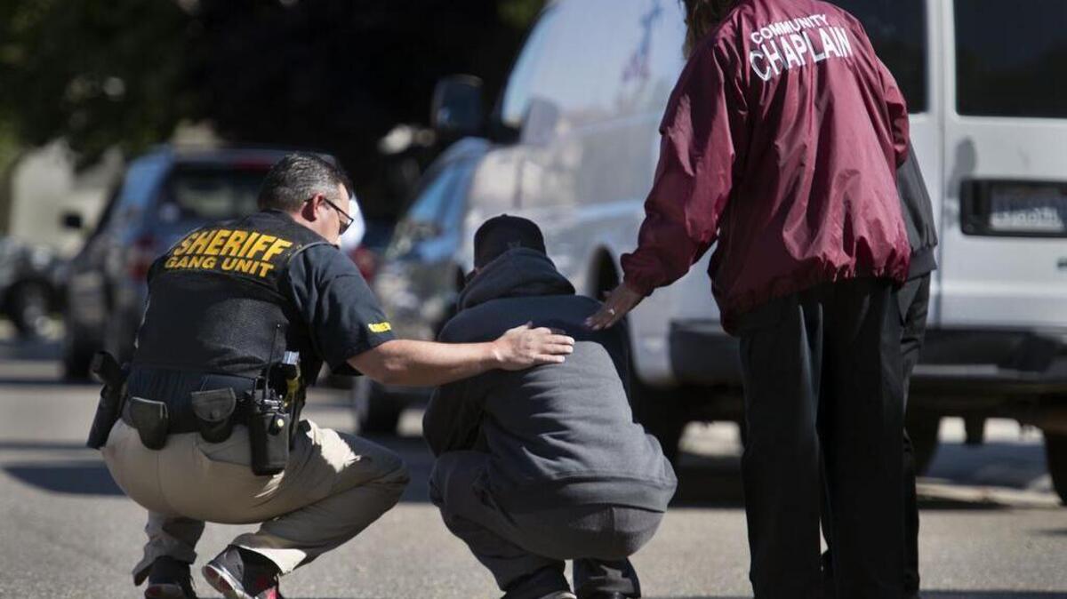 A Sacramento County Sheriff's deputy, left, and two chaplains comfort a family member of the shooting victims killed on Thursday, April 28, 2016, in Sacramento County south of the capital. Three men were shot to death in a house on Ardith Drive about 6:30 a.m. Other people in the house at the time were unharmed.