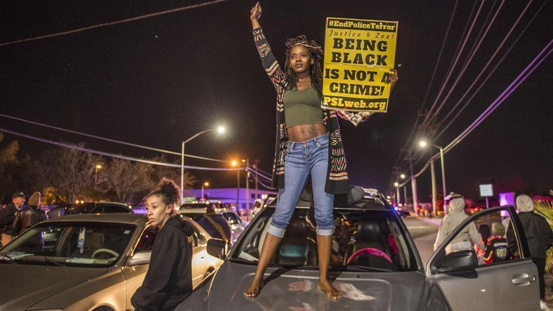 Kianshay Brown of Sacramento stands on a car on Meadoview Rd. as she joined participants of a candlelight vigil in honor of Stephon Clark who marched to the area near where Clark was shot at his grandparents home in Sacramento on Friday.