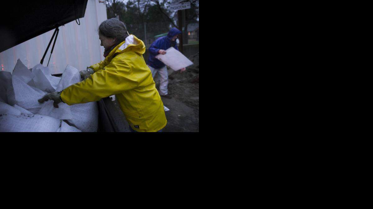 
Becca and Randy Smith prepare sandbags to protect their neighbor's home from the overflowing Arcade Creek at the corner of Pasadena Ave and Winding Way Thursday.
