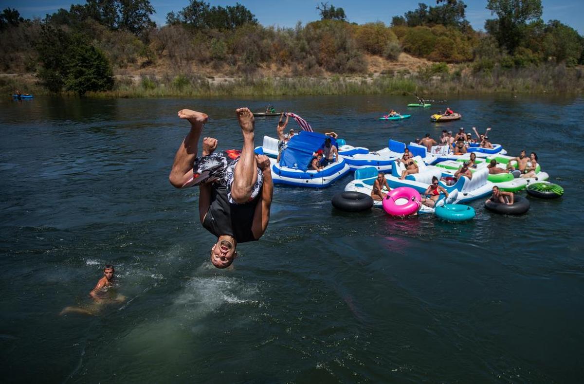 A rafter jumps off the cliffs of the Rossmoor Bar to catch up with his flotilla at the American River on Saturday, July 11, 2015, in Rancho Cordova, Calif. 