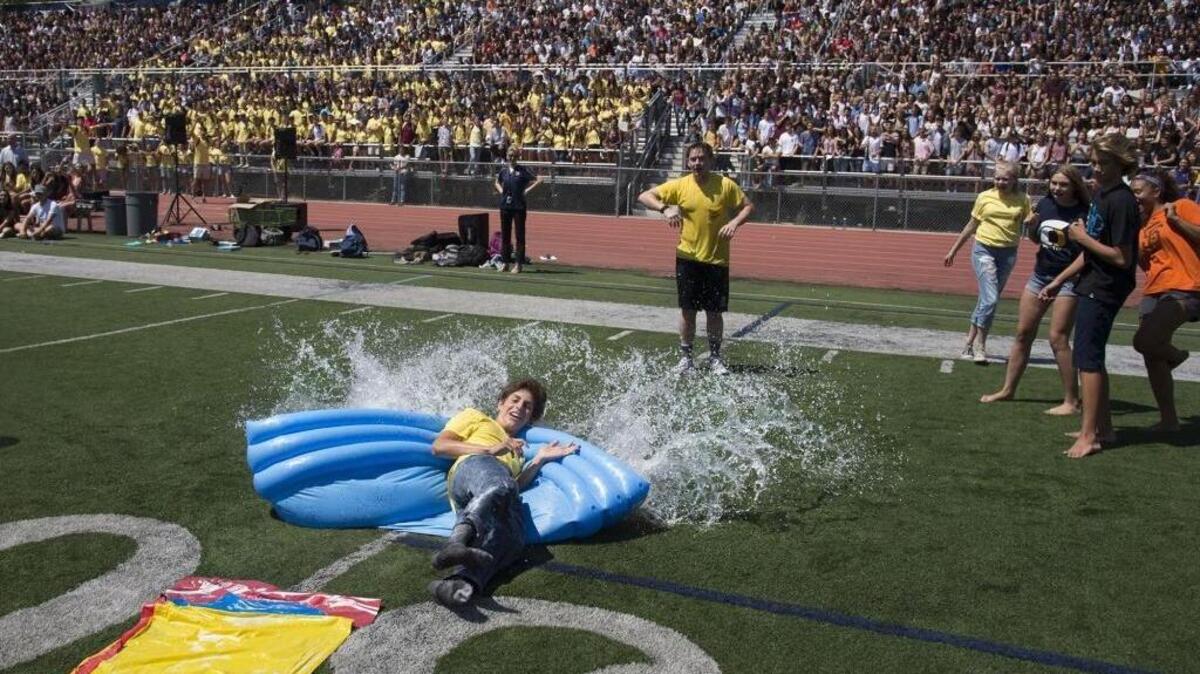 Ben Brandon, a senior at Oak Ridge High School, scores a run as he slides into a kids’ pool during a kickball game on the first day of school.