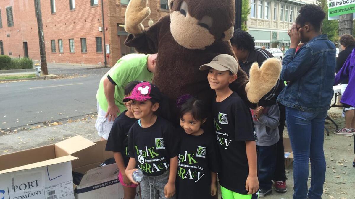 
Walk4Literacy participants Maiah Williams, left, Jayda Vogelsang and Brandon Vogelsang meet Curious George during Saturday’s event in Sacramento.
