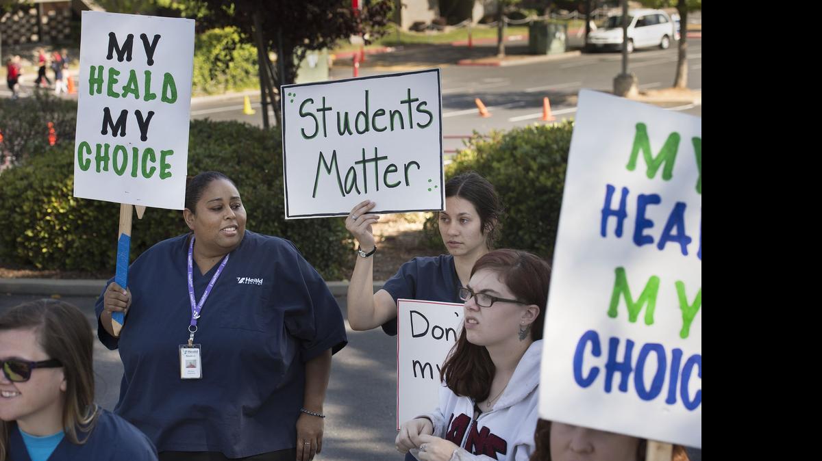 
Heald students Melissa Valentine, 35, left, and Aja Furgason, 24, background right, hold signs  near Heald College's campus in Roseville while demanding answers from administrators as they express their unhappiness with the college's abrupt closing.
