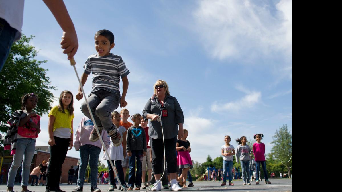 Michelle Yannacone, a third-grade teacher at Starr King elementary school, swings a jump rope for Hasan Aljanabi and other students during recess in 2015. California students will get a mandatory 30-minute recess under a new state law.