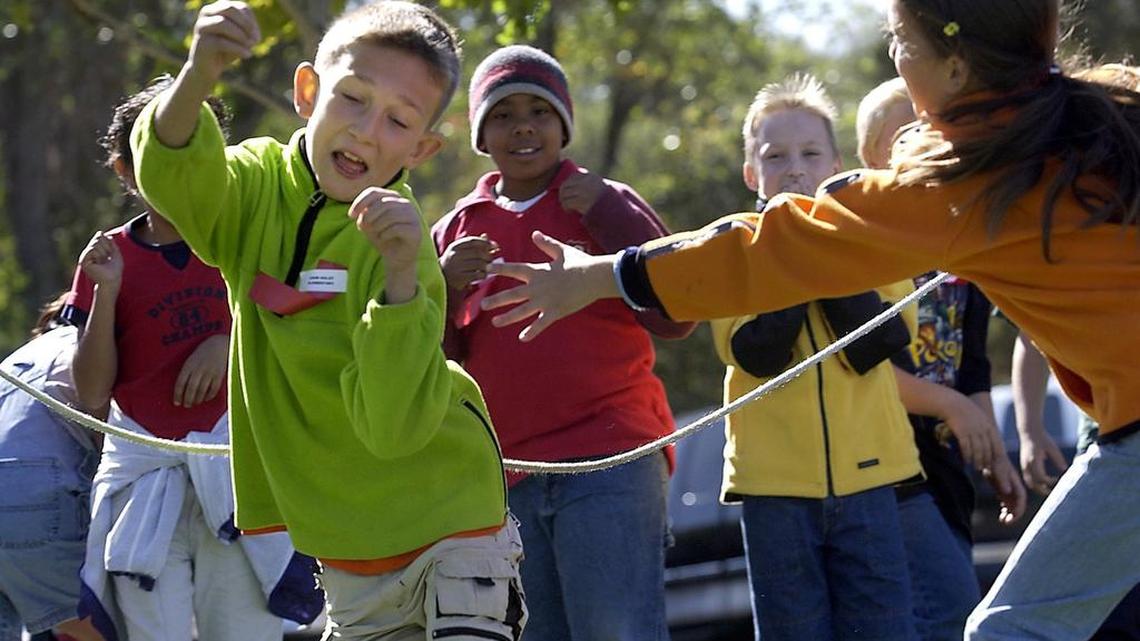 Kids at John Holst Elementary School play a game in which a student playing a salmon tries to make it downstream to the ocean without being eaten (tagged) by a predator, played by fellow students, Friday, October 10, 2003, at the American River Salmon Festival’s “Schools Day,” at Lake Natoma.