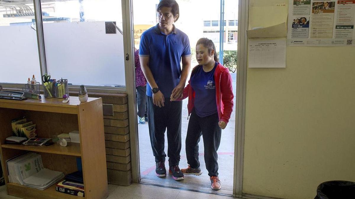 Special education teacher Paolo Legaspi, left, escorts student Linnette Her, 17, into class at Luther Burbank High School. Legaspi is on a temporary visa to work in the U.S. as a special education teacher. The district says there aren’t enough local teachers, so it recruits abroad.