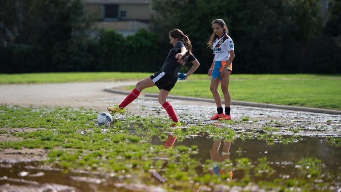 Freshman soccer player Siena Getz watches teammate Kelly Grimes extend herself in muddy terrain as she retrieves a ball on Monday, March 14, 2016 at McClatchy High School in Sacramento. Heavy rains and an inadequate draining system has allowed water to settle on the east end of the track.