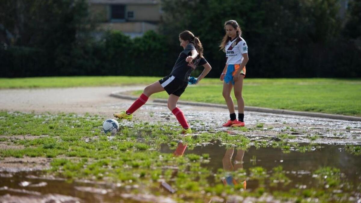 Freshman soccer player Siena Getz watches teammate Kelly Grimes extend herself in muddy terrain as she retrieves a ball on Monday, March 14, 2016 at McClatchy High School in Sacramento. Heavy rains and an inadequate draining system has allowed water to settle on the east end of the track.