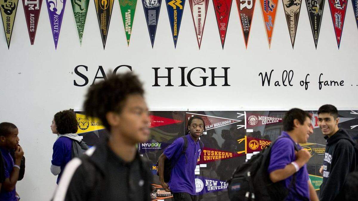 Sacramento Charter High School students walk past the ”wall of Fame” – the pennants represent colleges that former students have attended – in 2014.