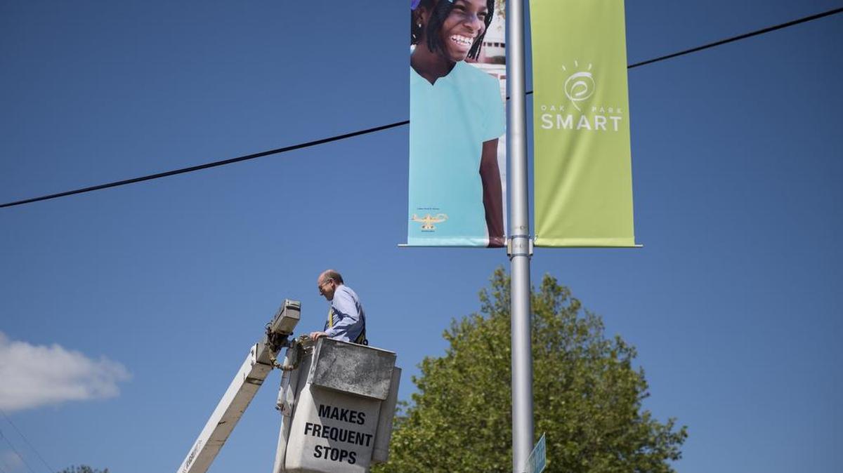 Councilman Jay Schenirer finishes hanging up banners Thursday to celebrate Oak Park schools and to honor eighth-grader Araba Cudjoe’s excellent grades and perfect attendance at Father Keith B. Kenny K-8 School in Sacramento. The banner campaign is part of a larger effort to make education in Oak Park a neighborhood concern.