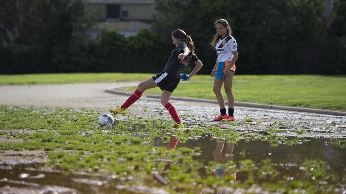 Soccer player Siena Getz watches teammate Kelly Grimes extend herself in muddy terrain as she retrieves a ball at McClatchy High School in Sacramento in 2015. Two years later, heavy rains and a inadequate draining system continue to allow water to settle on the east end of the track.