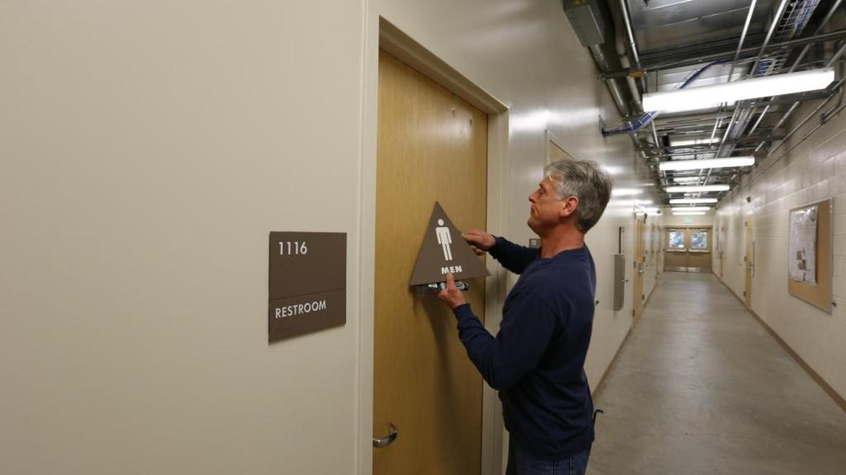 Mike Wais removes a men’s sign on a restroom door at the university’s School of Environmental and Plant Sciences, to replace it with one identifying the restroom as gender-inclusive. UC Davis is converting 120 restrooms across campus to gender-inclusive facilities.