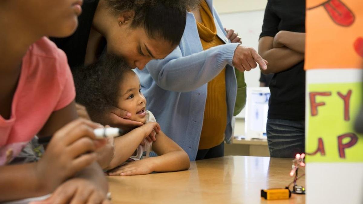 A crowd of eager family members and supporters, including Dajah Thomas of Sacramento and her niece, Nalayah Lindsey, 3, center, watch as Participants of Square Root Academy show off their engineering projects at John Still Middle School in south Sacramento on Saturday.