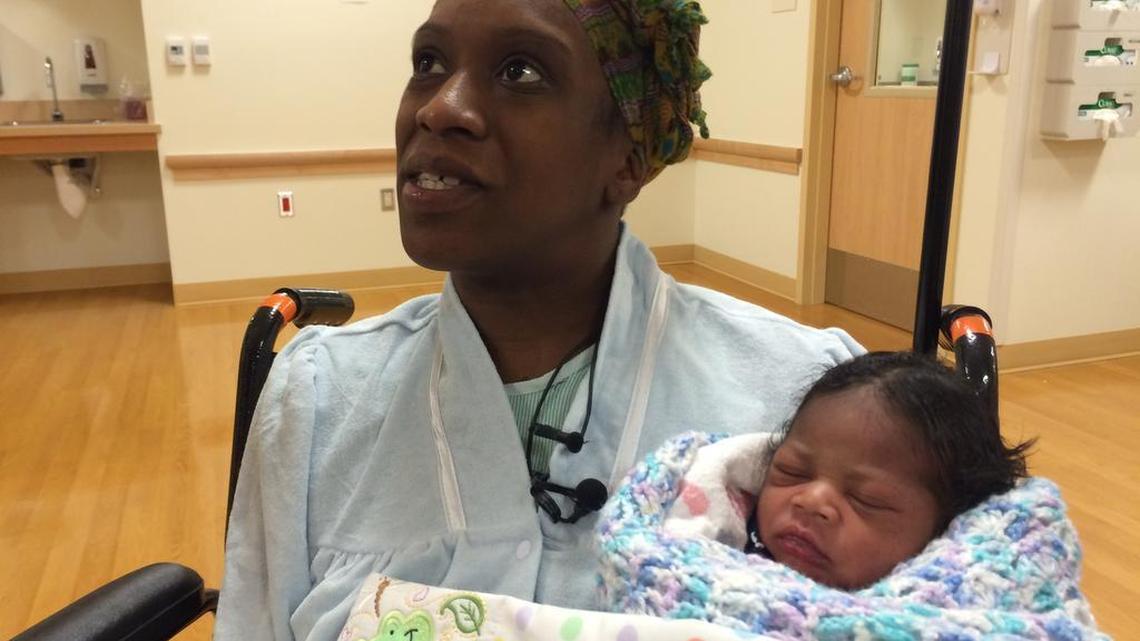 Iyshiah Lacey talks with reporters while holding her newborn child, Josiah DeAndre Jordan.
