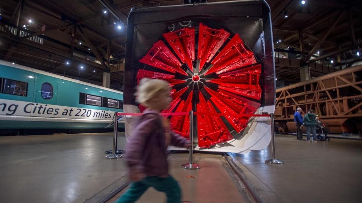 A youngster runs past a 251,000-pound rotary snowplow in a new exhibit with information about the history of train snow removal at the California State Railroad Museum in Sacramento on Friday.