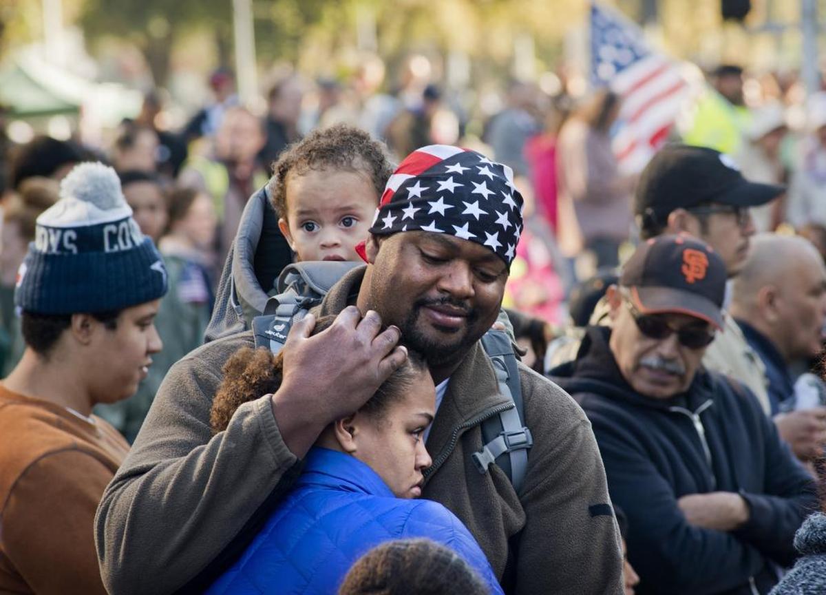 Jhason Wint of Sacramento hugs his daughter, Syraih, 14, while carrying his 18-month-old son, Khiernan, as they wait for the Veterans Day parade to begin. 