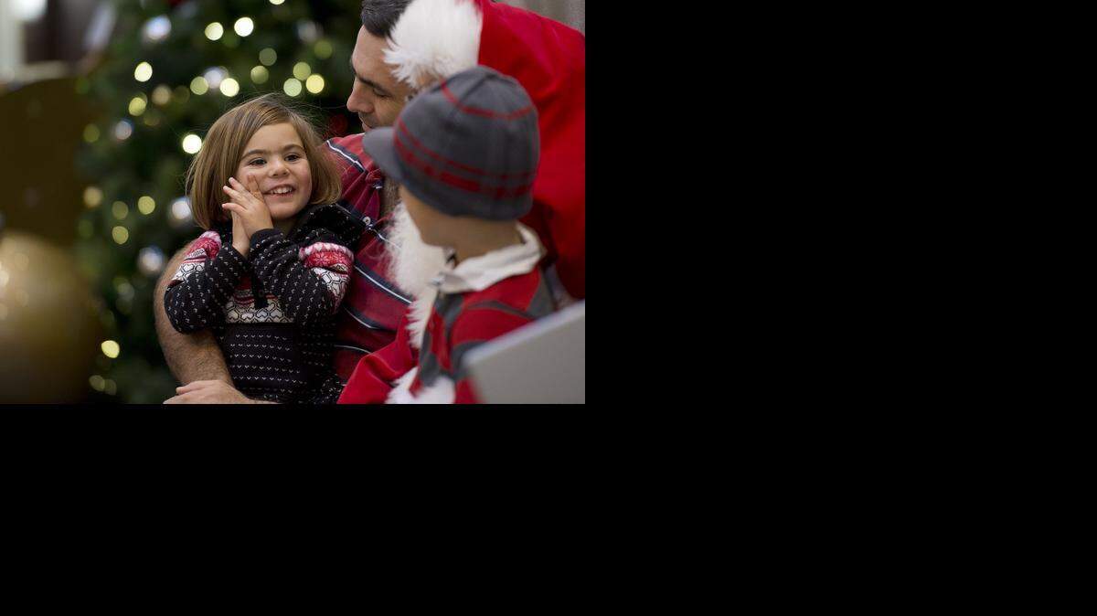 
Rebecca Farinha, 3, sits with her father, Mike, and brother, Jonathan, as they are photographed with Santa Claus at the Galleria on Monday.
