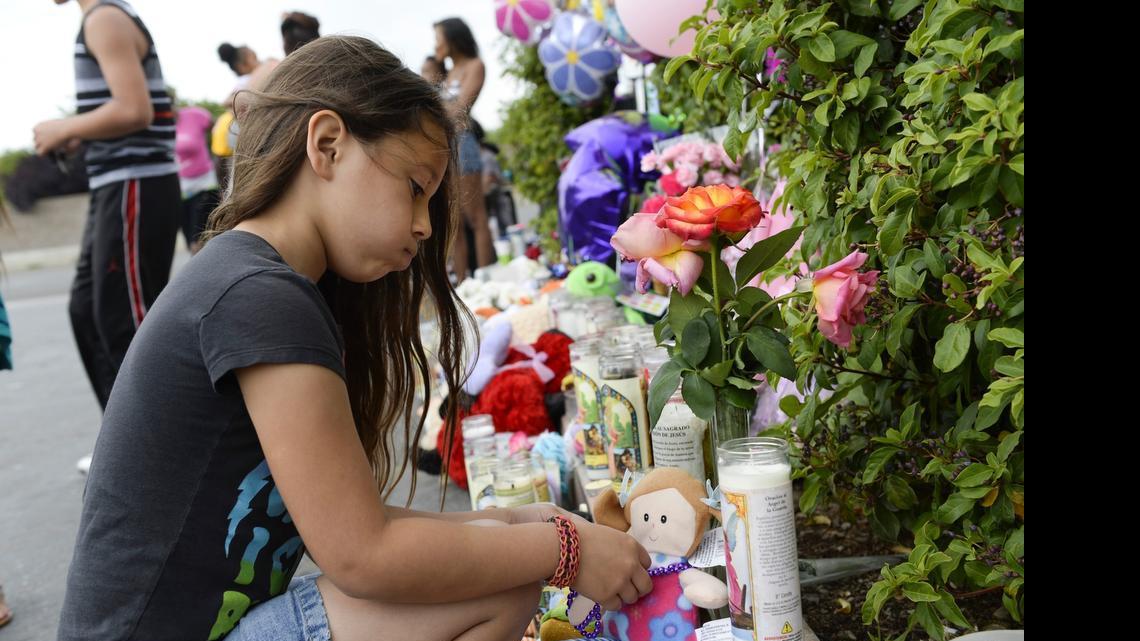 
Maiessa Treadway, 8, sighs as she puts a purple necklace on a doll to honor the memory of 6-year-old Jadianna Larsen.
