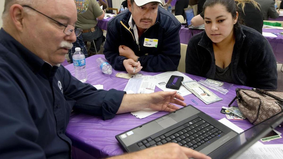 Michael Wilson, left, a certified Covered California agent helps Jose and Laura Gomez of south Sacramento with their choice for insurance coverage at the SEIU union hall on March 31, 2014, in Sacramento.