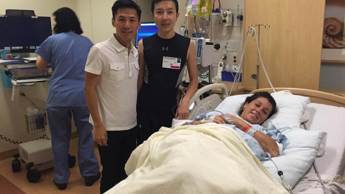 Surrogate mother Debi Lawson rests in the delivery room at Kaiser Roseville Medical Center with new parents Eric Yan, left, and Zhenxing Bao. They were matched with Nelson by a surrogacy agency. The parents could pay as much as $200,000 for the birth of Brenda.