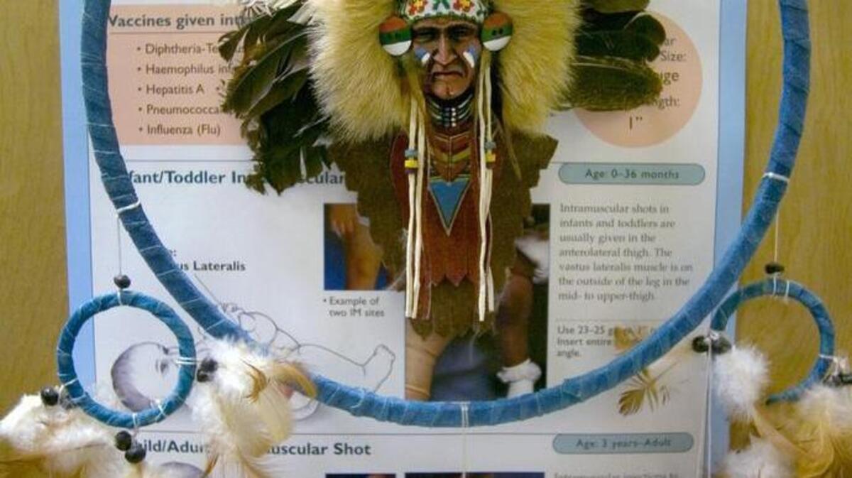A Native American Dream Catcher hangs on a lab room door over an immunization chart at the Native American Health Center.