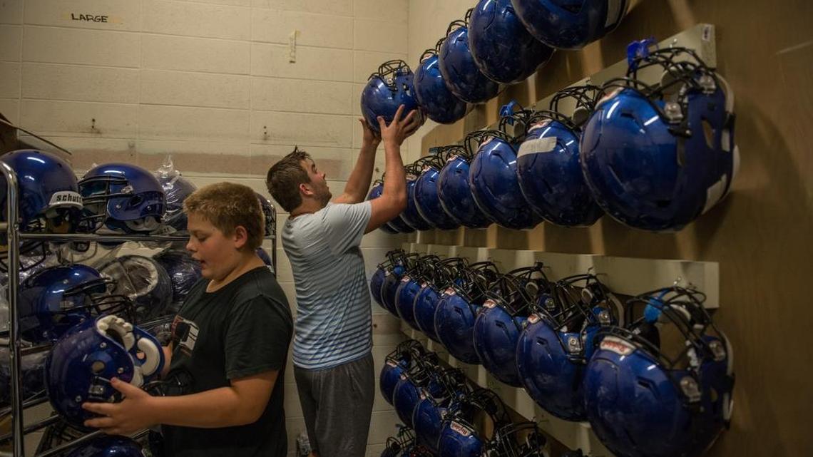 
Davis Senior High School lineman Brett Furtek, right, checks in his helmet on  Aug. 27. Davis Senior High now uses special helmets with sensors that alert coaches of impacts to the head. If a player experiences a hit within the “top 1 percent” of football impacts, the coaches and trainers are notified by a device on the sidelines. 
