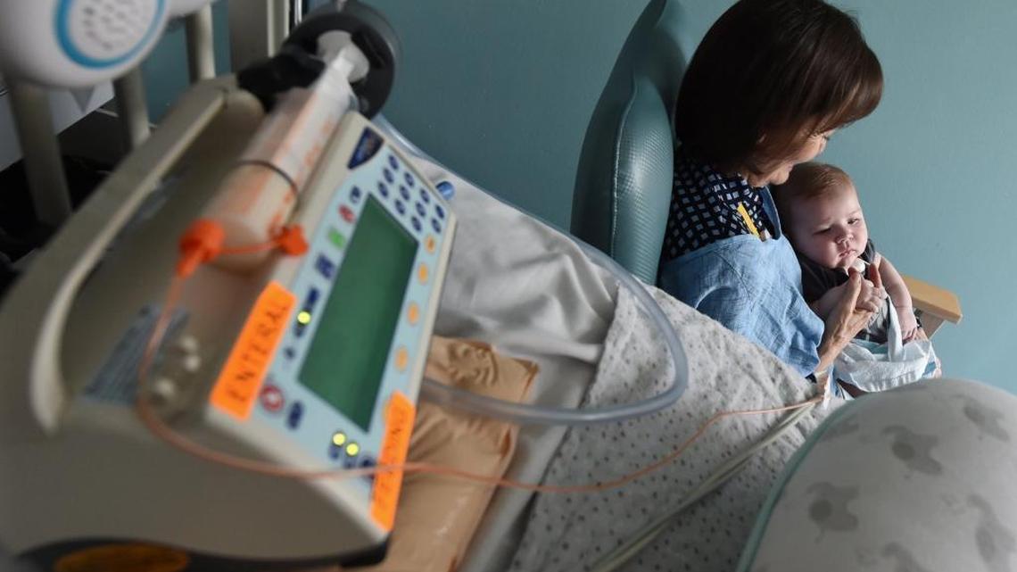 Valley Children’s Hospital volunteer cuddler Kerry Abbott cuddles Grant Early, nearly 4 months old, in the neonatal intensive care unit, as medical equipment he’s hooked up to sits nearby.
