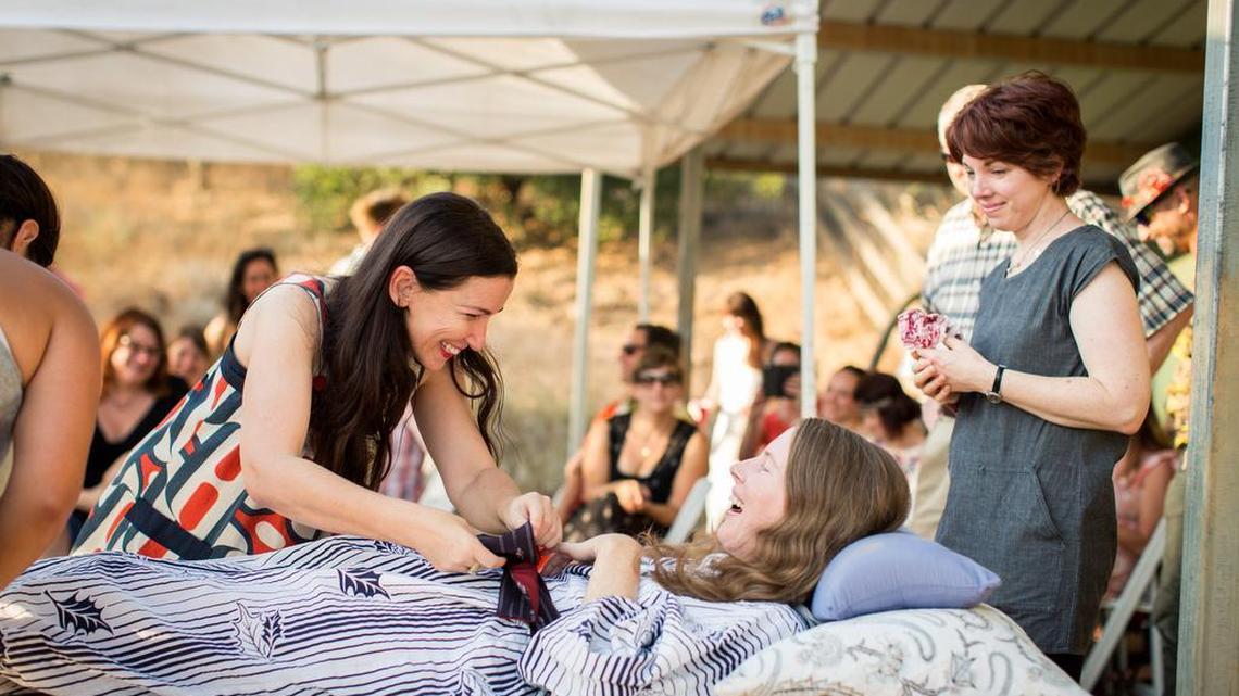 On July 24, Amanda Friedland, left, surrounded by friends and family, adjusts friend Betsy Davis’ sash as she lies on a bed during her “Right To Die Party” in Ojai. The 41-year-old woman, diagnosed with ALS, held the party to say goodbye before becoming one of the first California residents to take life-ending drugs under a new law that gave such an option to the terminally ill.